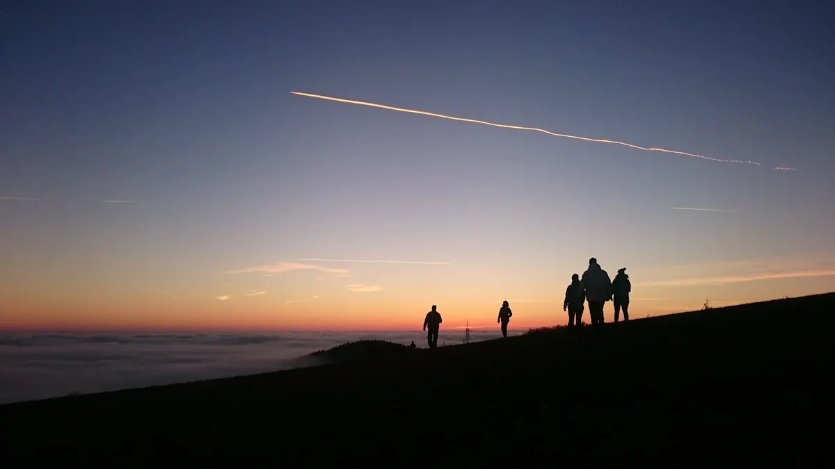 Silhouette d'un groupe marchant en montagne au coucher du soleil